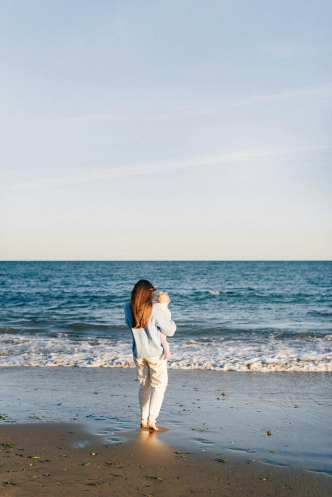 Eine Frau mit Kind auf dem Arm am Meer